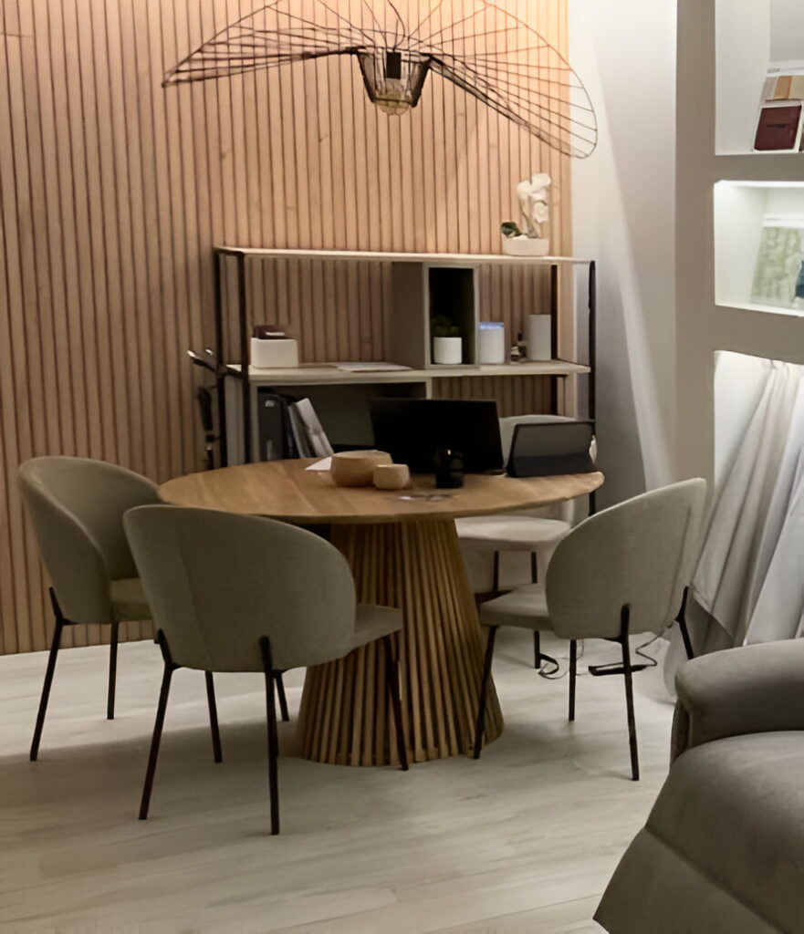 Mesa redonda de madera con cuatro sillas tapizadas alrededor en una sala de reuniones moderna